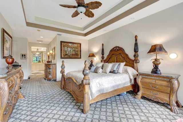 bedroom with connected bathroom, light carpet, visible vents, a ceiling fan, and a tray ceiling