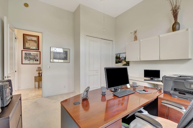 office space with light carpet and a towering ceiling