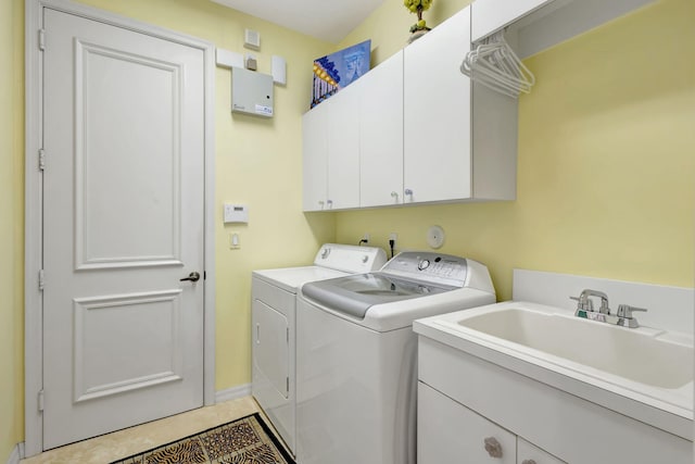 laundry room with light tile patterned flooring, cabinets, washer and dryer, and sink