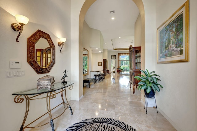 hall featuring arched walkways, recessed lighting, visible vents, baseboards, and marble finish floor