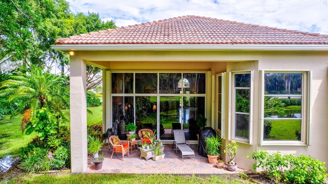 rear view of property with a patio area, stucco siding, and a tiled roof