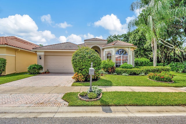 mediterranean / spanish-style house with an attached garage, a tiled roof, decorative driveway, and stucco siding