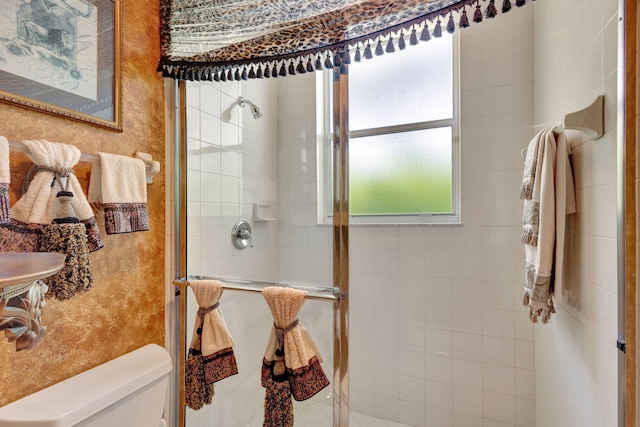 bathroom featuring toilet, an enclosed shower, and a wealth of natural light