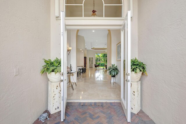 living area with visible vents, arched walkways, marble finish floor, a tray ceiling, and french doors