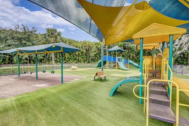 community jungle gym featuring fence and a yard