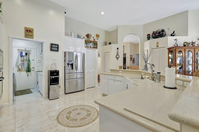 kitchen featuring white cabinets, a high ceiling, sink, and stainless steel fridge