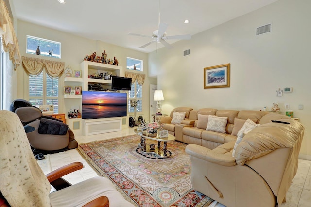 living room with light tile patterned flooring, a towering ceiling, and ceiling fan