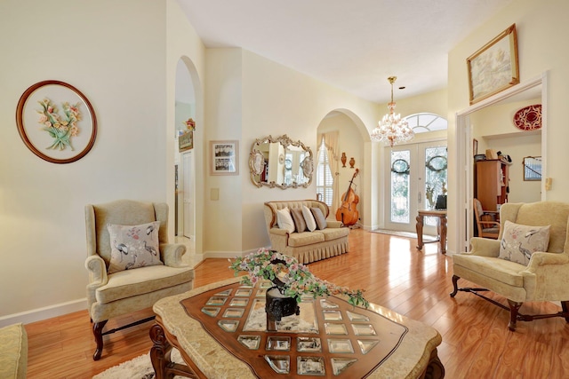 living room featuring french doors, a chandelier, and light hardwood / wood-style floors