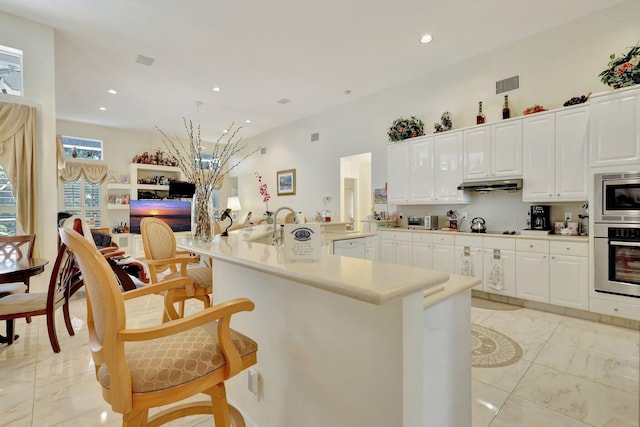 kitchen with appliances with stainless steel finishes, a breakfast bar area, and white cabinets