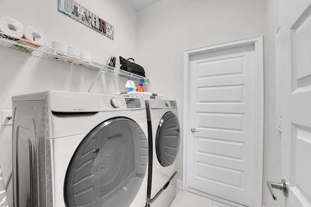 laundry room featuring washer and clothes dryer and light tile patterned flooring