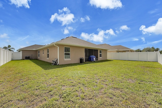 back of house featuring central AC unit and a yard