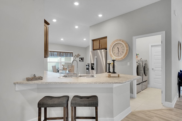 kitchen featuring sink, stainless steel fridge, a kitchen breakfast bar, separate washer and dryer, and kitchen peninsula