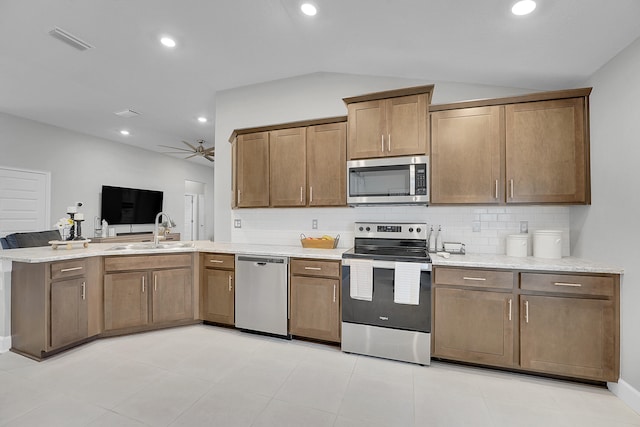 kitchen featuring lofted ceiling, sink, backsplash, and appliances with stainless steel finishes