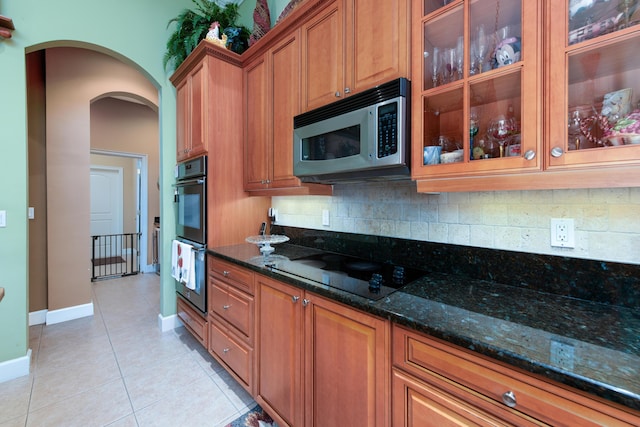 kitchen with tasteful backsplash, light tile patterned floors, black appliances, and dark stone counters