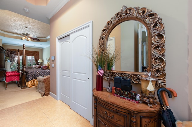 carpeted foyer entrance with a tray ceiling, crown molding, and ceiling fan