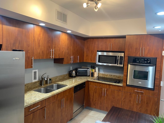 kitchen featuring appliances with stainless steel finishes, sink, and light stone counters