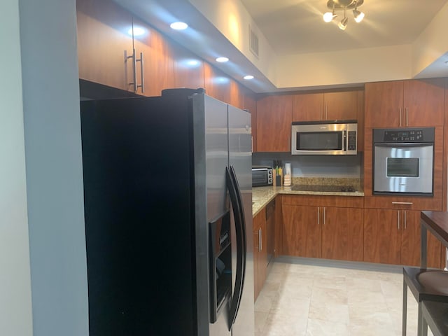 kitchen with light stone counters and appliances with stainless steel finishes