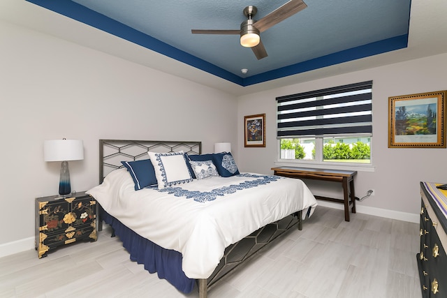 bedroom with a raised ceiling and ceiling fan