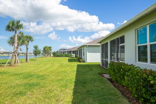 view of yard with a sunroom and a water view