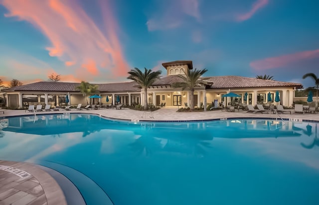 pool at dusk with a patio area