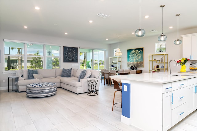 kitchen featuring a kitchen island with sink, plenty of natural light, sink, and white cabinetry