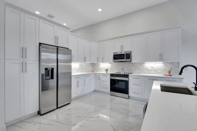 kitchen featuring stainless steel appliances, white cabinetry, sink, and decorative backsplash