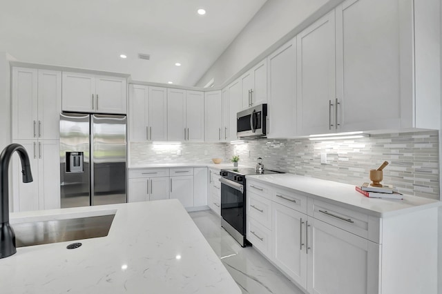 kitchen featuring light stone counters, white cabinets, sink, backsplash, and appliances with stainless steel finishes