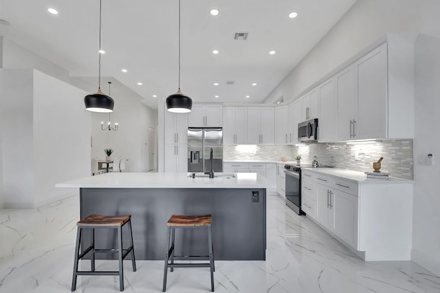 kitchen featuring white cabinets, a center island with sink, decorative light fixtures, and appliances with stainless steel finishes