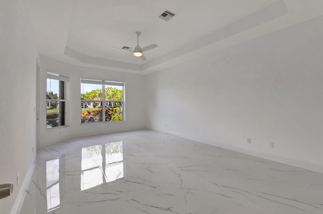 spare room with ceiling fan and a raised ceiling