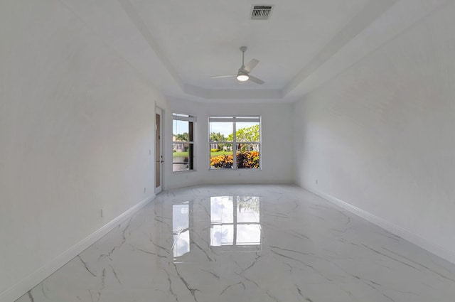 empty room featuring ceiling fan and a raised ceiling