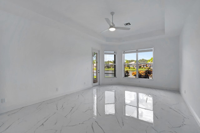 empty room featuring ceiling fan and a raised ceiling