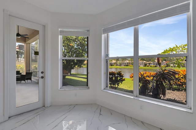 unfurnished sunroom with ceiling fan, a healthy amount of sunlight, and a water view