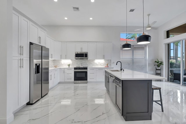 kitchen featuring hanging light fixtures, white cabinetry, sink, and appliances with stainless steel finishes