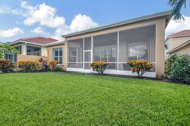 rear view of property featuring a sunroom and a lawn