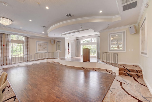 interior space with light wood-type flooring, a raised ceiling, a healthy amount of sunlight, and crown molding