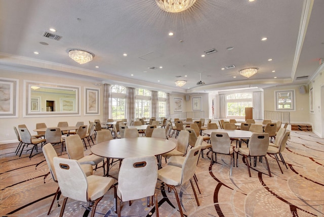 dining space with ornamental molding, a textured ceiling, a raised ceiling, and an inviting chandelier