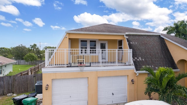 view of front of house featuring central air condition unit, a balcony, and a garage