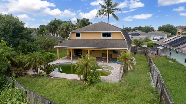 back of property featuring a fenced in pool, a patio area, and a lawn