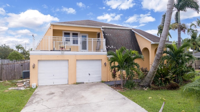 view of front facade featuring a balcony, a front lawn, and a garage