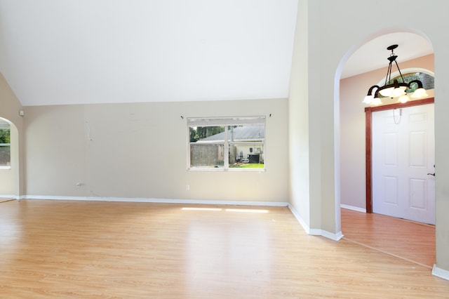 entrance foyer featuring lofted ceiling, light hardwood / wood-style flooring, and an inviting chandelier