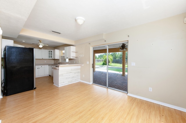 kitchen featuring white cabinetry, kitchen peninsula, light hardwood / wood-style floors, and black fridge