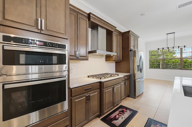 kitchen featuring hanging light fixtures, light tile patterned floors, wall chimney exhaust hood, backsplash, and stainless steel appliances