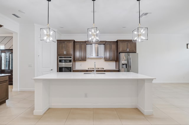 kitchen with pendant lighting, a large island with sink, range hood, stainless steel appliances, and dark brown cabinetry