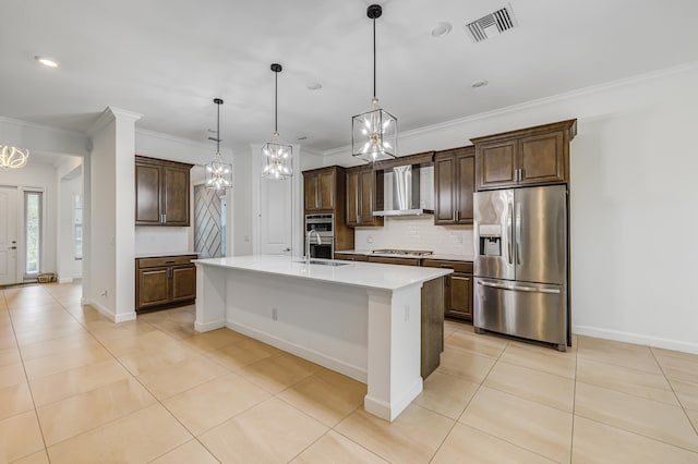 kitchen featuring pendant lighting, sink, wall chimney exhaust hood, a center island with sink, and appliances with stainless steel finishes