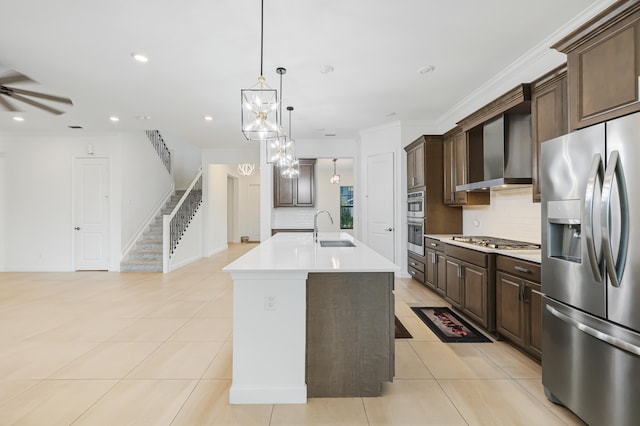 kitchen with appliances with stainless steel finishes, an island with sink, wall chimney exhaust hood, pendant lighting, and sink