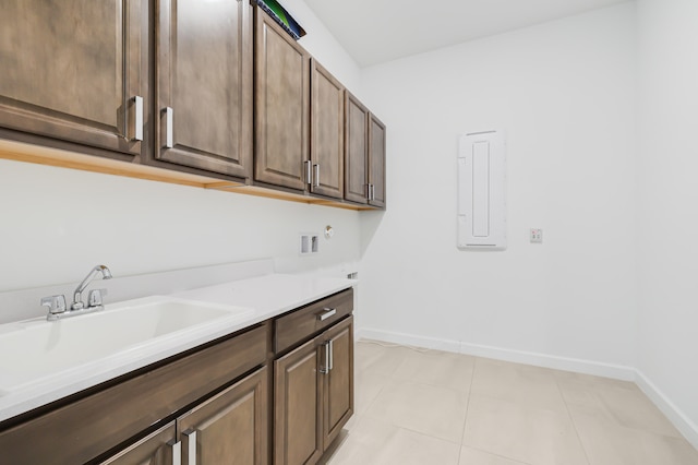 laundry area with cabinets, washer hookup, electric panel, light tile patterned flooring, and sink