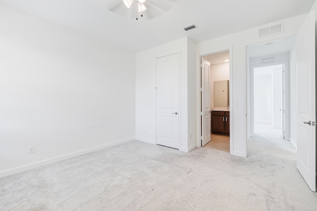 unfurnished bedroom with ensuite bathroom, ceiling fan, and light colored carpet