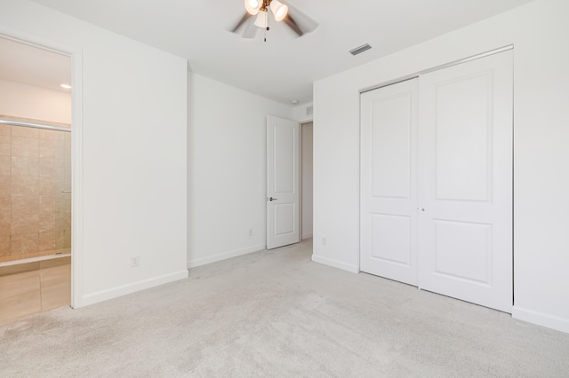 unfurnished bedroom with ceiling fan, light colored carpet, a closet, and connected bathroom