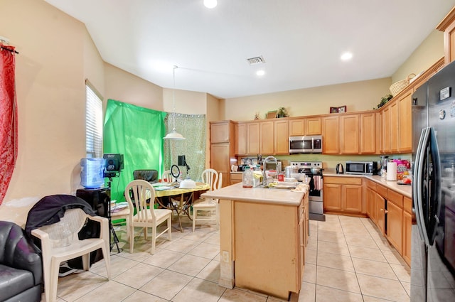 kitchen with light tile patterned floors, stainless steel appliances, decorative light fixtures, a kitchen island with sink, and sink