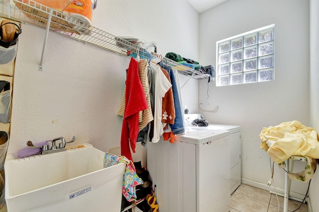 clothes washing area with baseboards, separate washer and dryer, a sink, laundry area, and tile patterned flooring